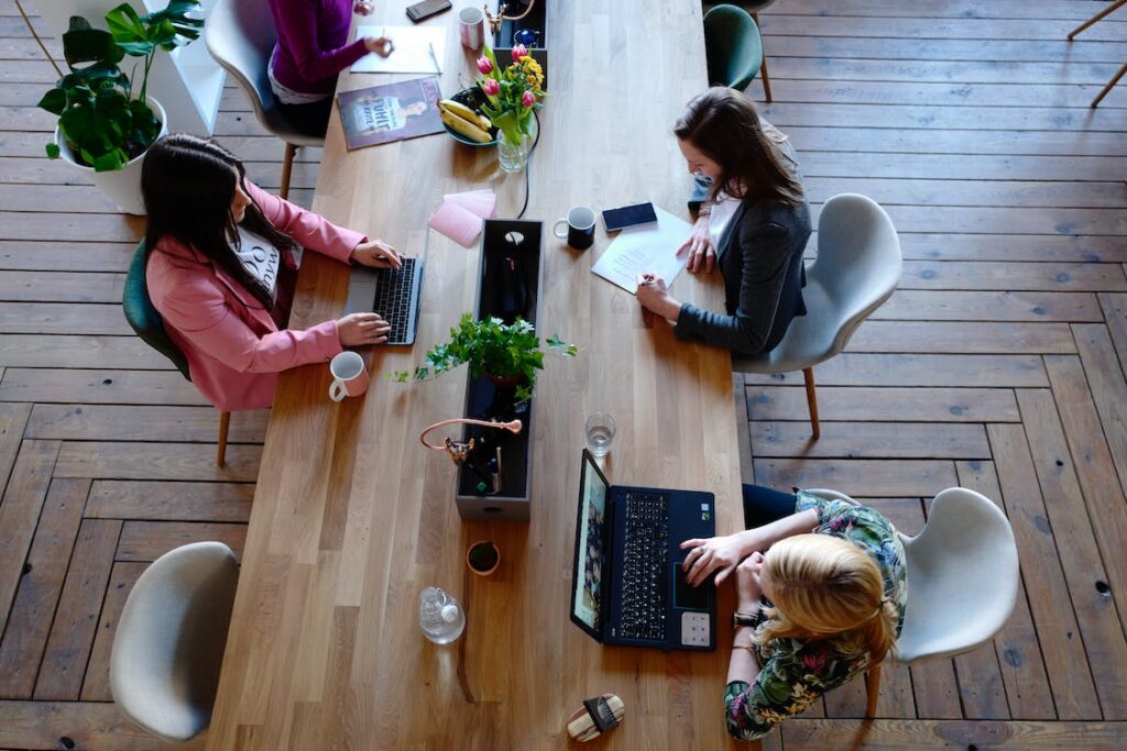 Gruppe an Personen an einem Holztisch mit Laptops