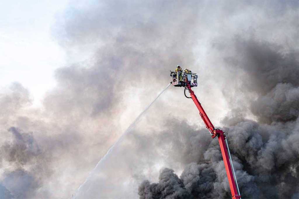 Das Bild zeigt eine Feuerwehr-Drehleiter, welche einen Großbrand löscht.