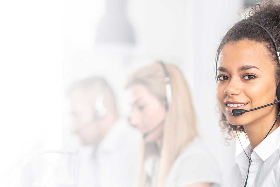 Das Bild zeigt eine Frau im Callcenter mit aufgesetztem Headset.