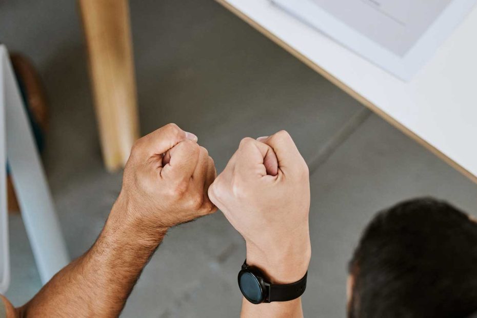 Das Bild zeigt zwei Call-Center-Agenten, welche mit einem Fist Bump einen Deal feiern.